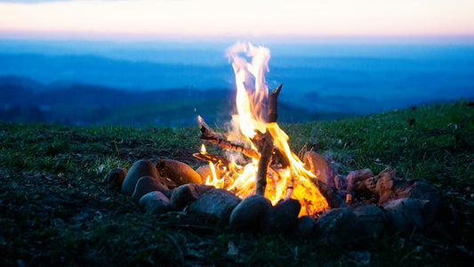 Foc de tabără cu munți în fundal